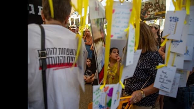 <ruby ><rb><span class="jlpt-n1" word="人質">人質</span></rb><rt>ひとじち</rt></ruby><span class="" word="の">の</span><ruby ><rb><span class="" word="帰">帰</span></rb><rt>かえ</rt></ruby><span class="" word="り">り</span><span class="" word="を">を</span><ruby ><rb><span class="" word="待">待</span></rb><rt>ま</rt></ruby><span class="" word="つ">つ</span><ruby ><rb><span class="jlpt-n5" word="家族">家族</span></rb><rt>かぞく</rt></ruby><span class="" word="と">と</span><ruby ><rb><span class="unknown" word="人々">人々</span></rb><rt>ひとびと</rt></ruby><span class="" word="の">の</span><ruby ><rb><span class="" word="気">気</span><span class="" word="持">持</span></rb><rt>きも</rt></ruby><span class="" word="ち">ち</span>